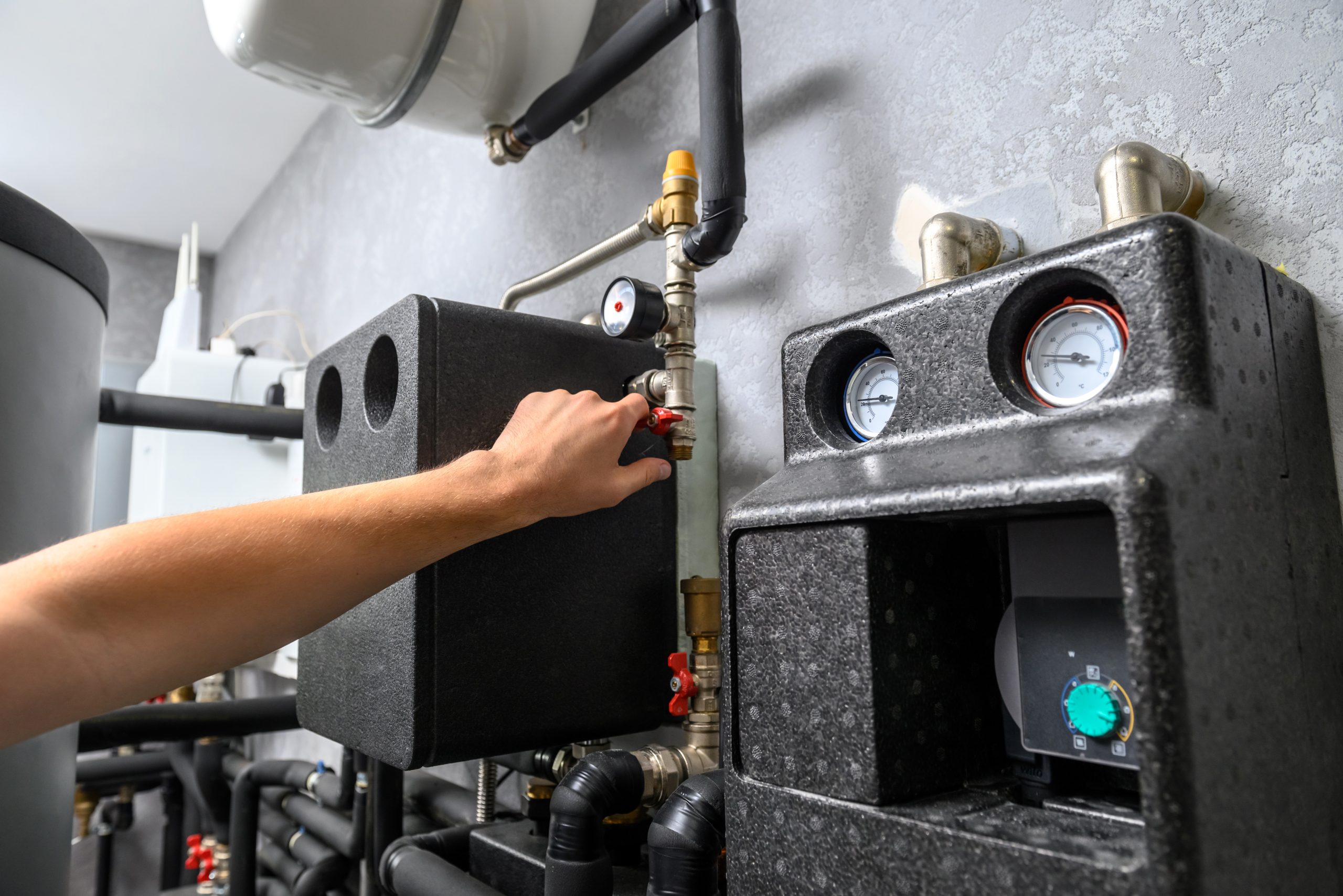 Modern electric boiler room in the house. Equipment for water heating system with automatic control unit. Close-up of a man's hand